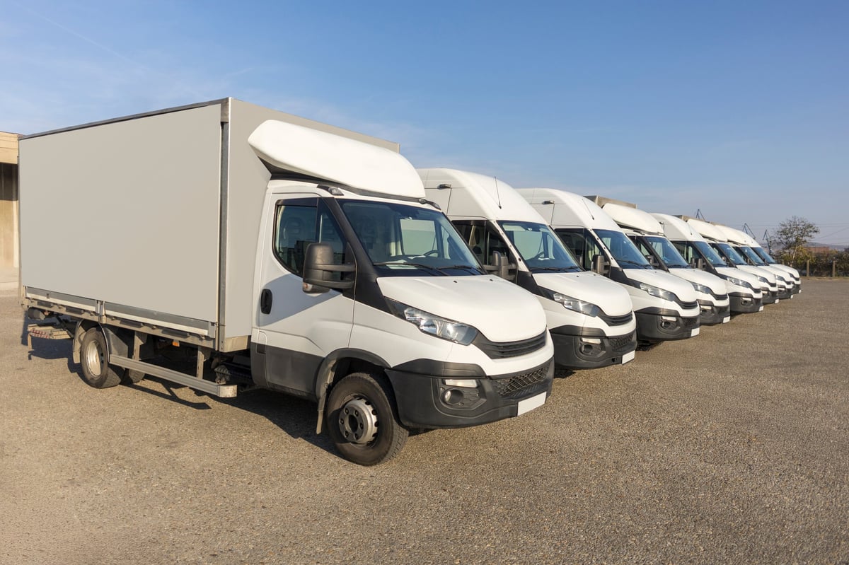 Fleet of white delivery trucks parked in a row at a logistics yard