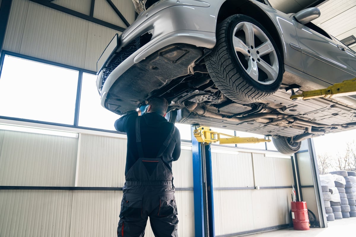 Car raised on a lift in a professional car service bay with the hood open