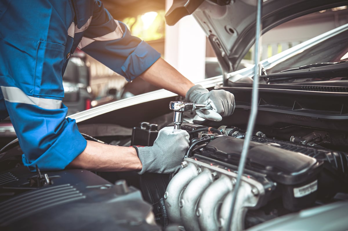 Technician using a wrench to repair an engine problem in a car