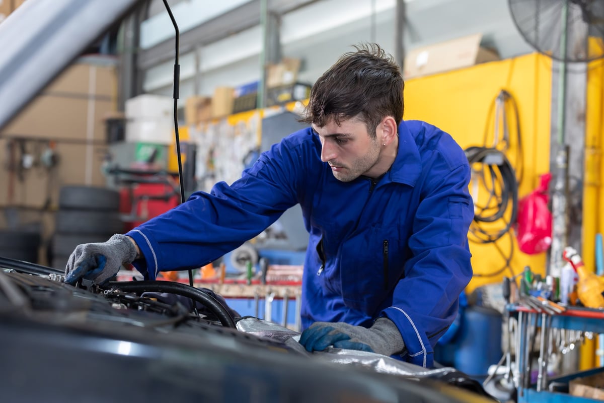 Caucasian mechanic repairs car engine in garage